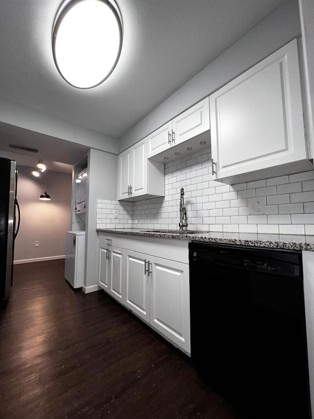 kitchen with white cabinetry, black dishwasher, sink, stainless steel fridge, and stacked washer and dryer