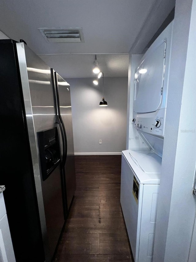 washroom featuring stacked washer / drying machine and dark hardwood / wood-style floors