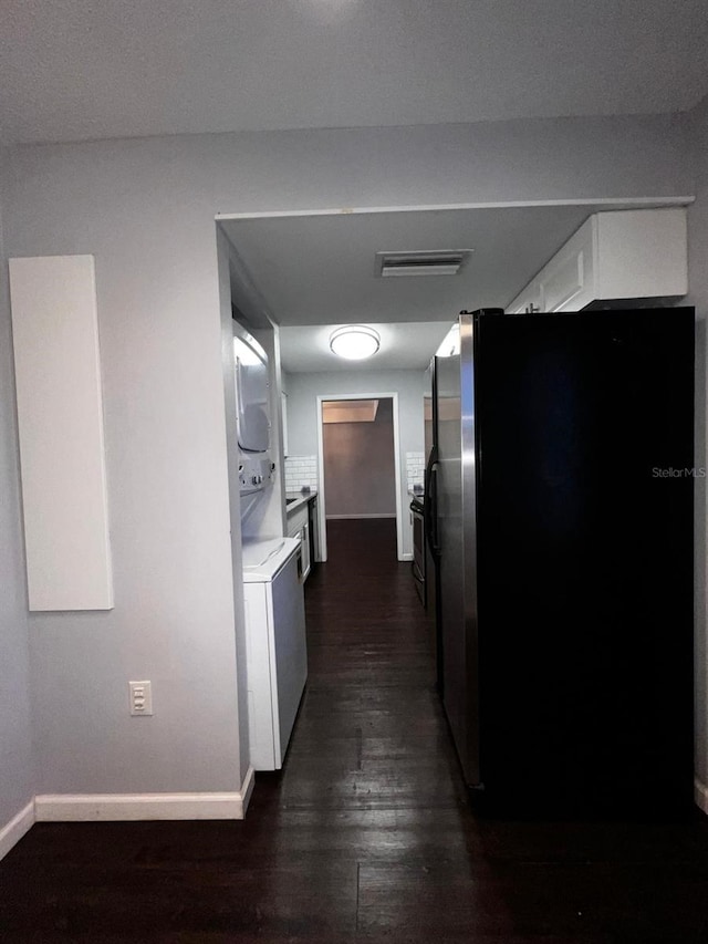 corridor with dark hardwood / wood-style flooring and stacked washer and clothes dryer