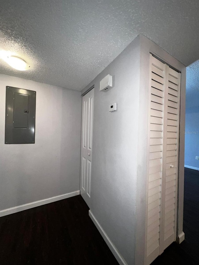 corridor with dark wood-type flooring, electric panel, and a textured ceiling