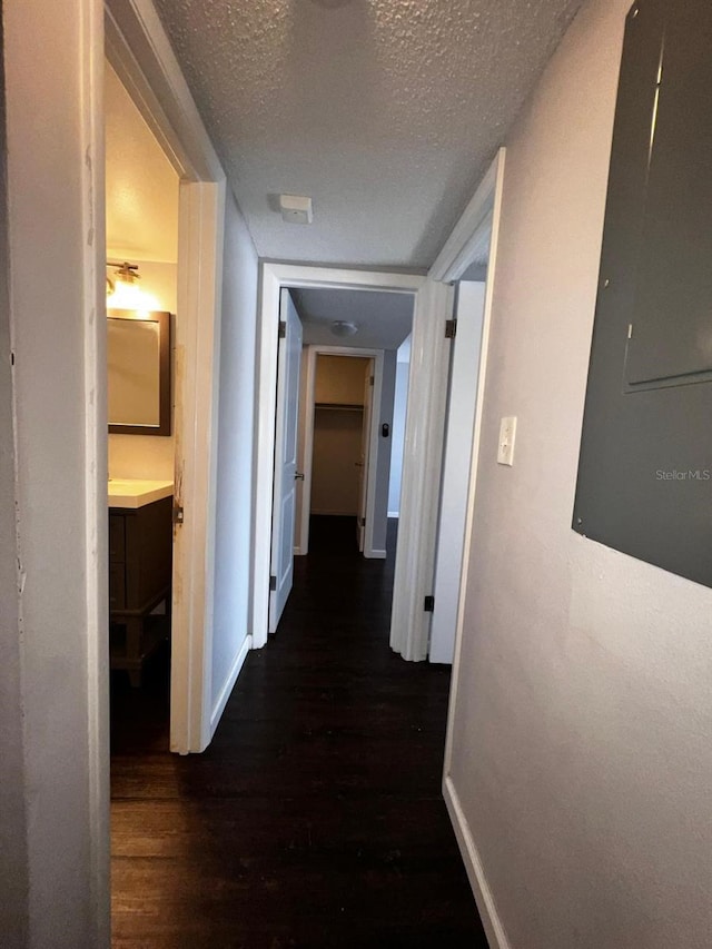 corridor featuring dark hardwood / wood-style floors, electric panel, and a textured ceiling