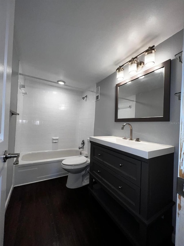 full bathroom featuring tiled shower / bath, vanity, toilet, and hardwood / wood-style floors