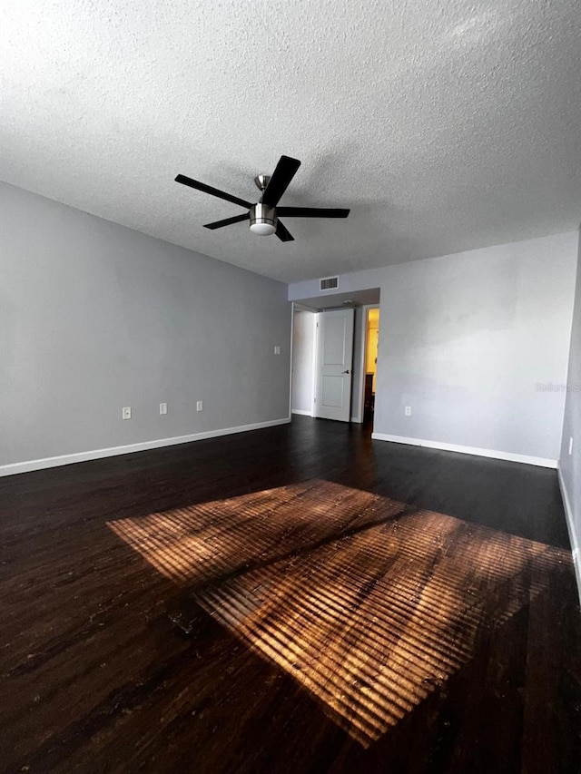 empty room featuring ceiling fan, dark hardwood / wood-style floors, and a textured ceiling