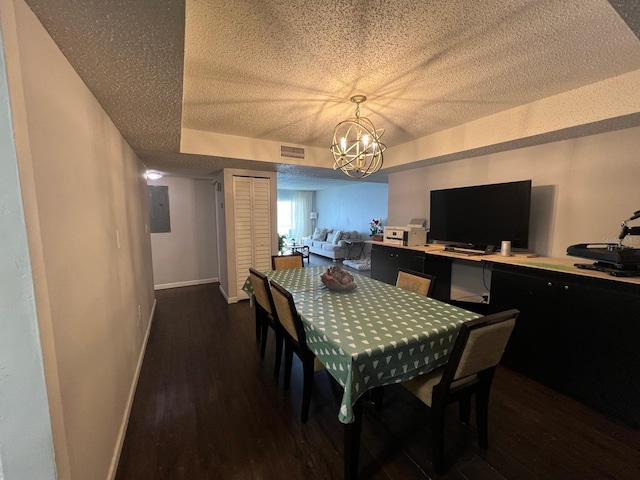 dining area featuring a textured ceiling, dark hardwood / wood-style flooring, electric panel, a raised ceiling, and a notable chandelier