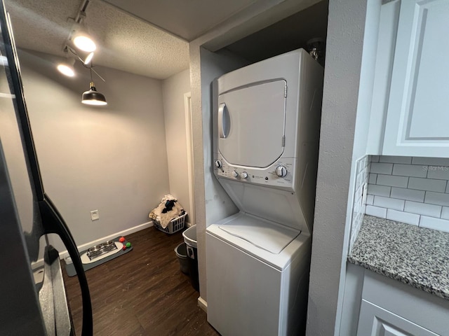 washroom with stacked washer / dryer, dark hardwood / wood-style floors, and a textured ceiling