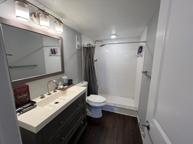 bathroom with walk in shower, toilet, wood-type flooring, a textured ceiling, and vanity