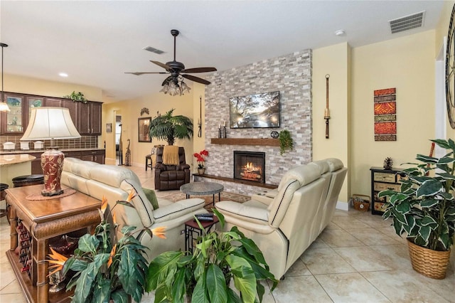 living room featuring light tile patterned floors, a stone fireplace, and ceiling fan