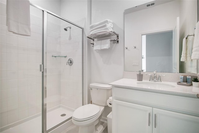 bathroom featuring vanity, a shower with door, and toilet