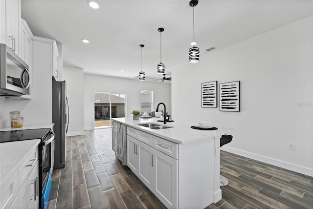 kitchen with white cabinetry, sink, stainless steel appliances, and an island with sink