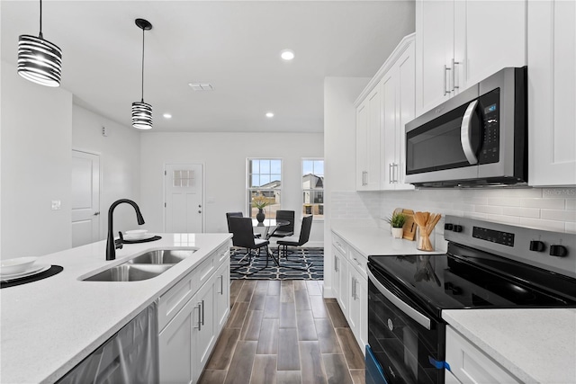 kitchen with stainless steel appliances, white cabinetry, sink, and pendant lighting