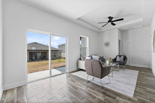 living room with ceiling fan and a tray ceiling