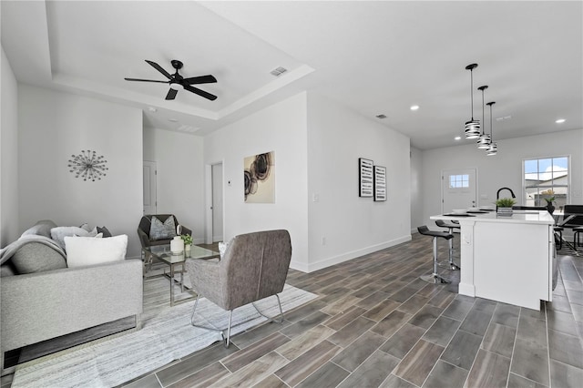 living room featuring ceiling fan and a tray ceiling