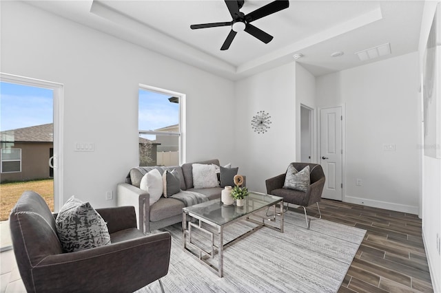 living room with a raised ceiling and a healthy amount of sunlight