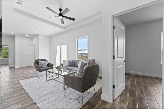 living room featuring ceiling fan and a raised ceiling