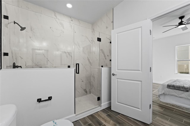 bathroom featuring ceiling fan, toilet, and a shower with shower door