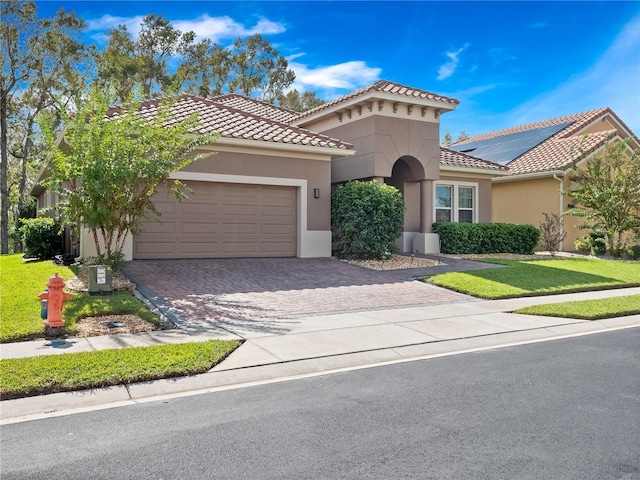 mediterranean / spanish house with a garage and a front lawn