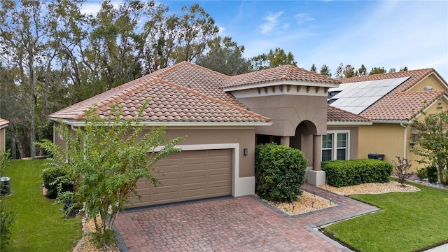 mediterranean / spanish-style house with a garage, a front yard, and solar panels