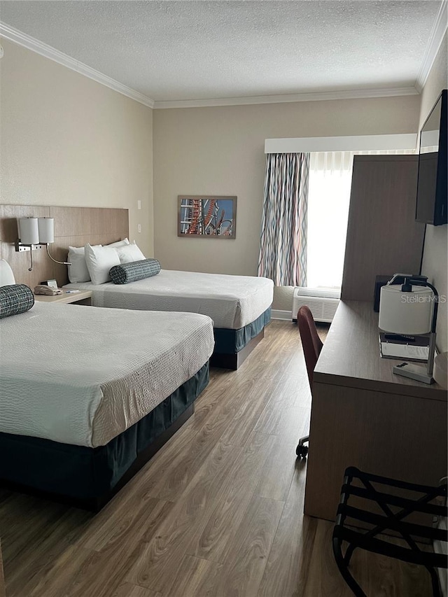 bedroom with wood-type flooring, ornamental molding, and a textured ceiling