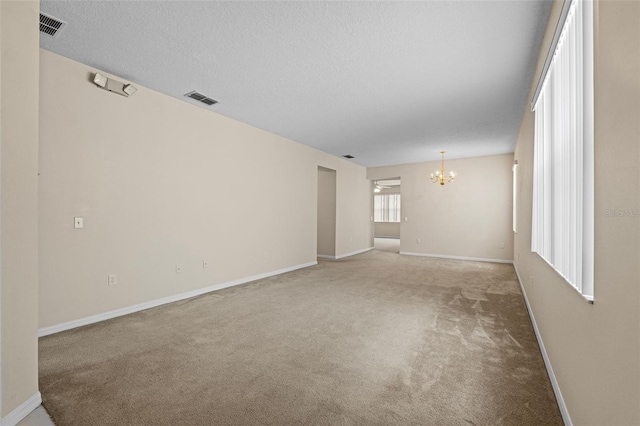 spare room featuring an inviting chandelier and carpet flooring