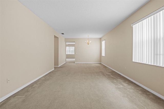 carpeted empty room featuring a chandelier