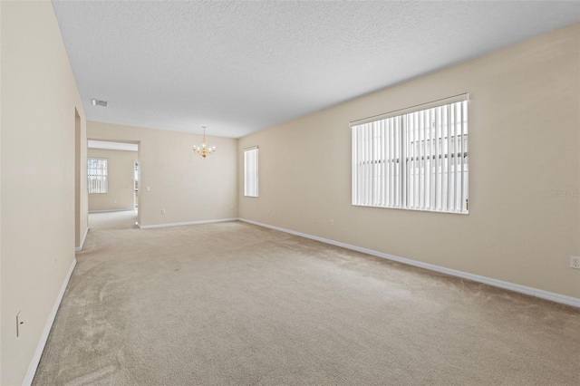 carpeted empty room with an inviting chandelier and a textured ceiling