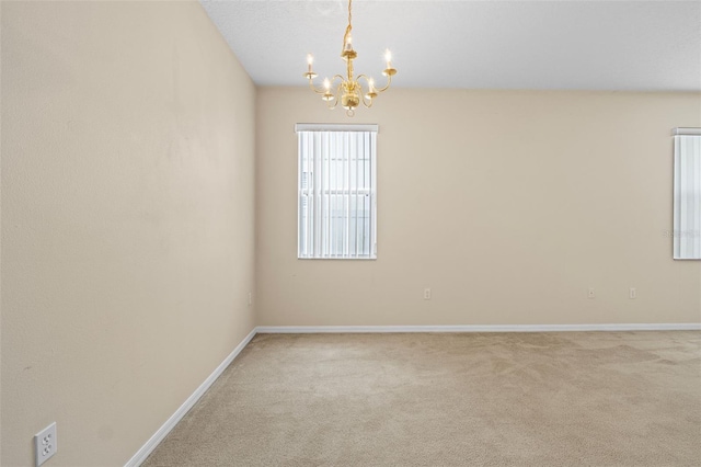 carpeted empty room featuring a chandelier