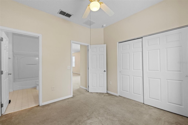 unfurnished bedroom featuring ensuite bathroom, light colored carpet, ceiling fan, and a closet