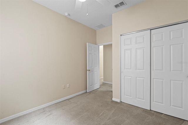 unfurnished bedroom featuring ceiling fan, light colored carpet, and a closet