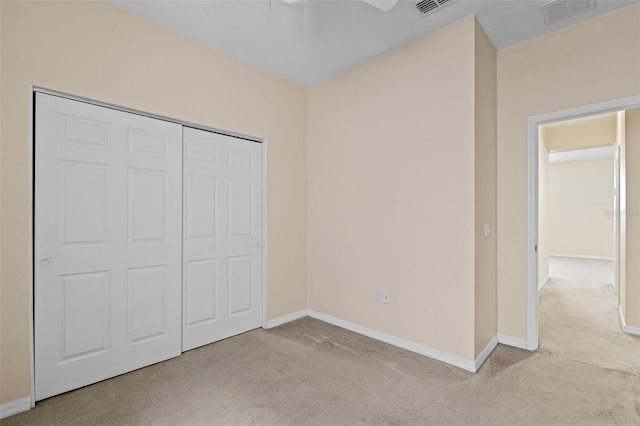 unfurnished bedroom featuring light carpet, a closet, and ceiling fan