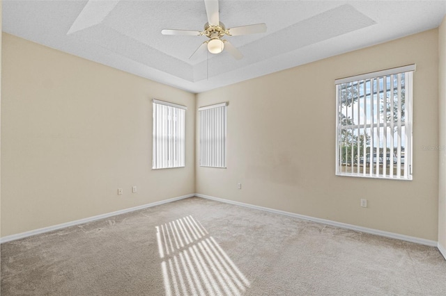 carpeted spare room featuring ceiling fan, a tray ceiling, and a textured ceiling