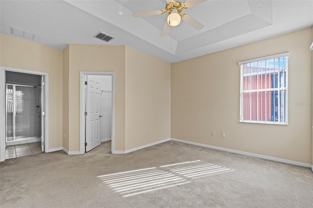 carpeted spare room featuring ceiling fan and a tray ceiling