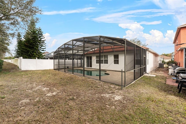 back of property featuring a fenced in pool, a patio area, glass enclosure, and a lawn