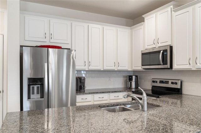 kitchen with sink, white cabinetry, stone counters, stainless steel appliances, and decorative backsplash