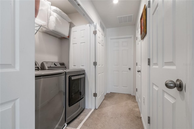 clothes washing area featuring light colored carpet and washing machine and clothes dryer