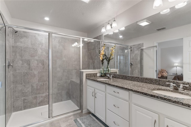 bathroom featuring vanity, tile patterned floors, a textured ceiling, and a shower with shower door