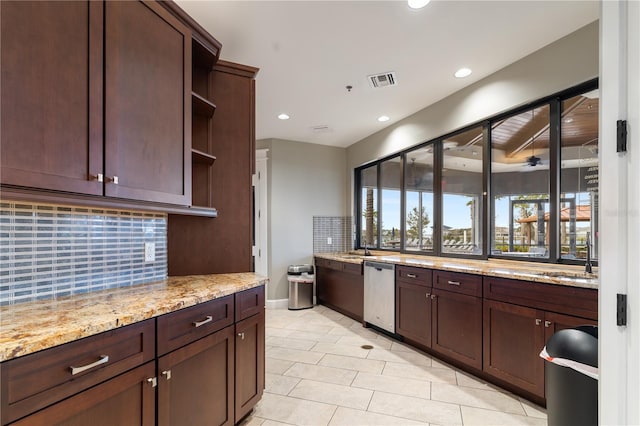 kitchen with dark brown cabinetry, light stone countertops, backsplash, and stainless steel dishwasher