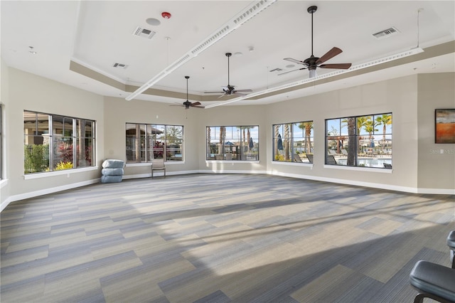 living room featuring a raised ceiling, plenty of natural light, and carpet flooring