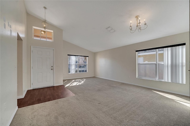 carpeted entryway with an inviting chandelier, a healthy amount of sunlight, and high vaulted ceiling