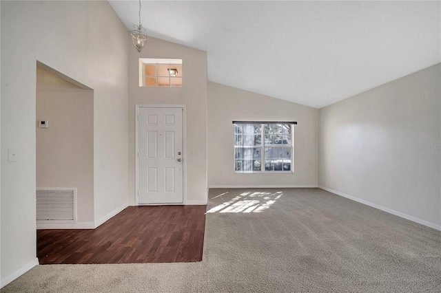 carpeted foyer featuring high vaulted ceiling