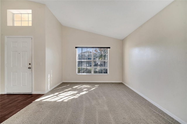 carpeted entrance foyer featuring vaulted ceiling