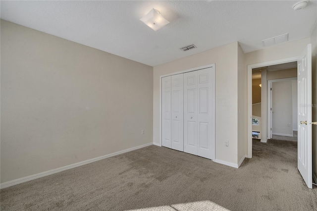 unfurnished bedroom featuring a closet, light carpet, and a textured ceiling