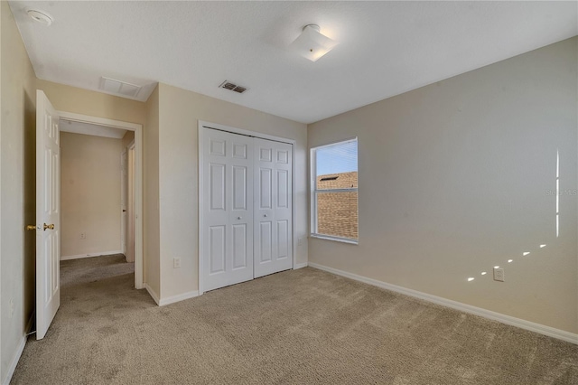 unfurnished bedroom with light colored carpet and a closet