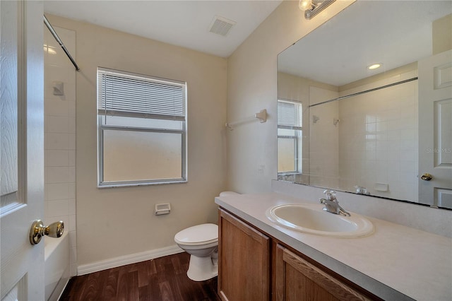 full bathroom with vanity, hardwood / wood-style floors, tiled shower / bath combo, and toilet