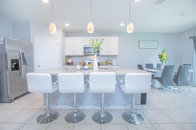 kitchen featuring stainless steel appliances, an island with sink, pendant lighting, and white cabinets