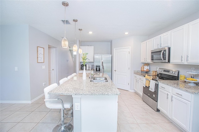 kitchen with stainless steel appliances, a kitchen island with sink, white cabinets, and decorative light fixtures