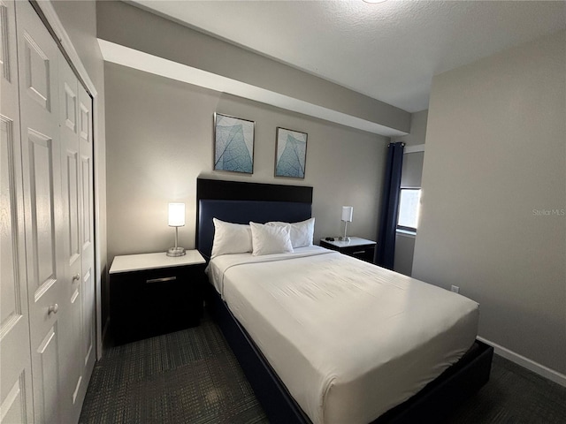 bedroom with dark carpet, a textured ceiling, and a closet