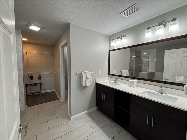 bathroom featuring vanity, tile patterned flooring, a shower with door, and a textured ceiling