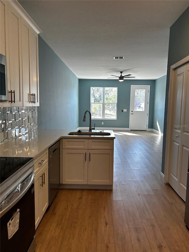 kitchen with stainless steel range with electric stovetop, kitchen peninsula, sink, and white cabinets