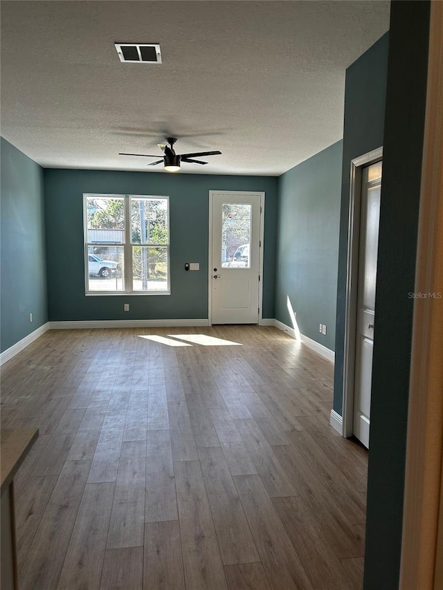 entryway with ceiling fan, a textured ceiling, and light wood-type flooring