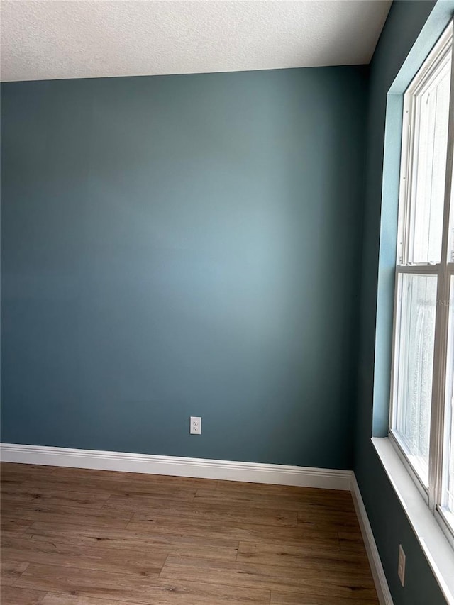 unfurnished room with wood-type flooring and a textured ceiling